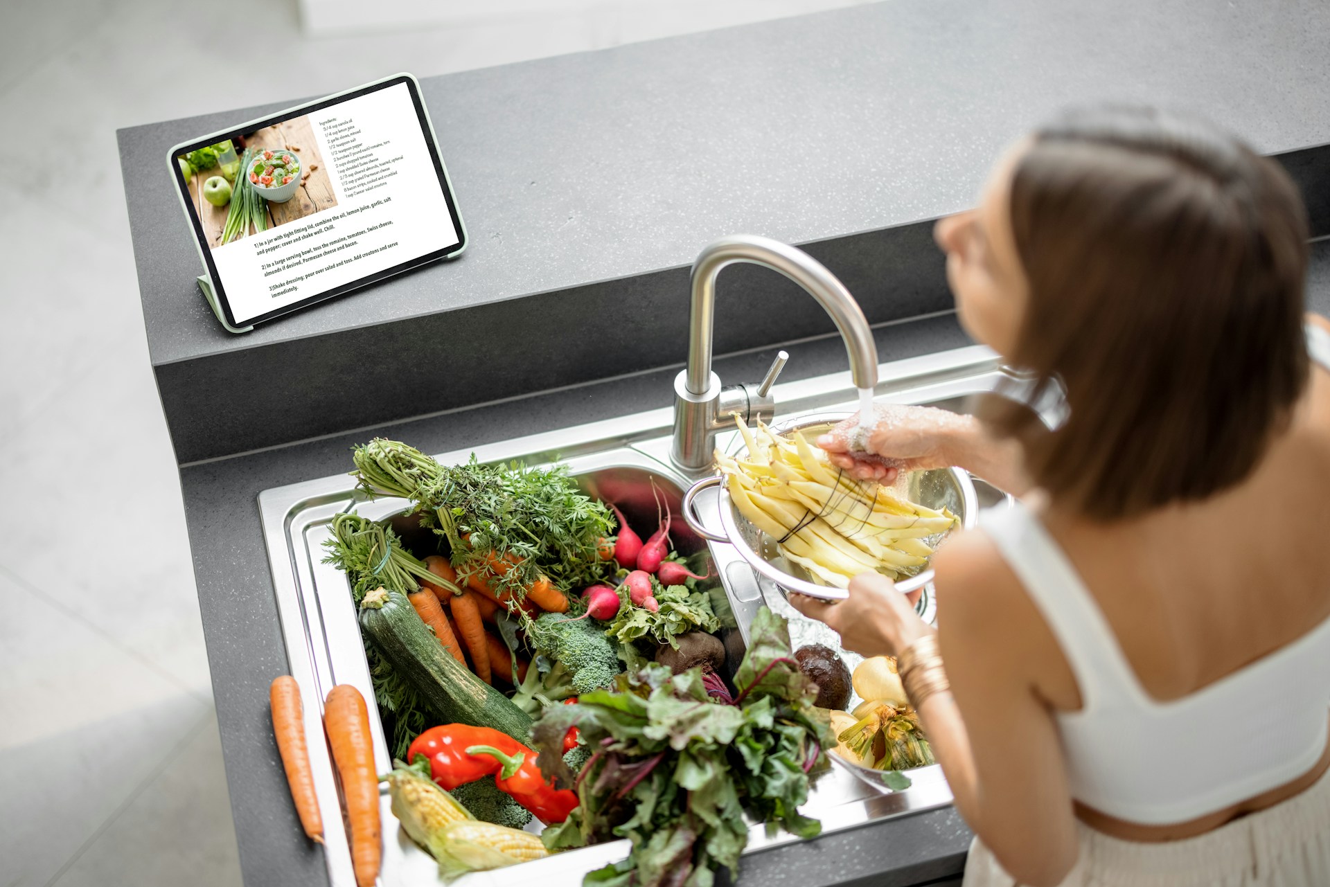 woman washing vegetables in sink